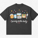 Printora UK charcoal heavyweight cotton t-shirt featuring a colourful Serving Smiles Daily school lunch graphic