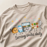 Printora UK natural stone heavyweight cotton t-shirt featuring a cute Serving Smiles Daily school lunch graphic