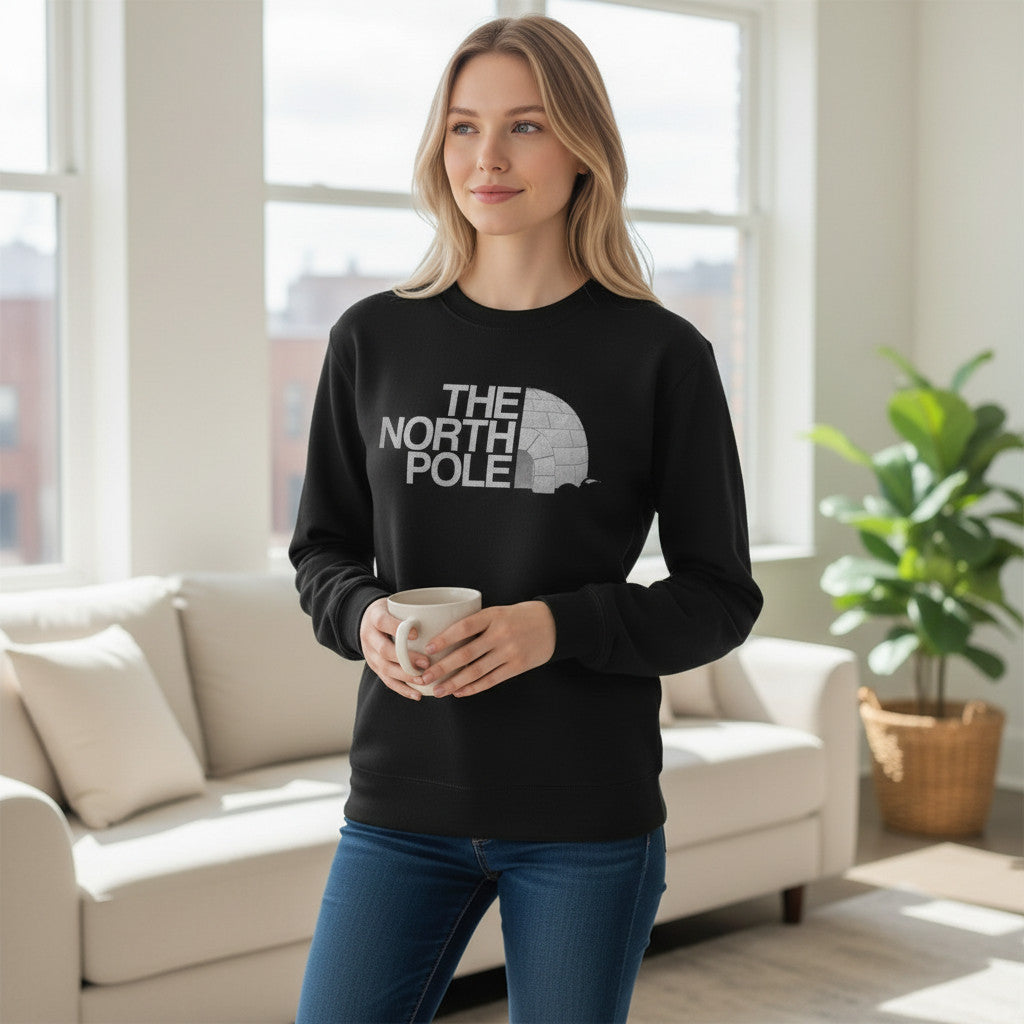 Printora UK black crew neck Christmas jumper with The North Pole igloo logo worn by a woman holding a mug